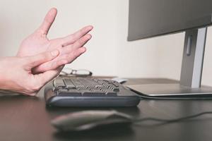 cerrar el dolor de manos por trabajar en la computadora, concepto de síndrome de oficina. foto