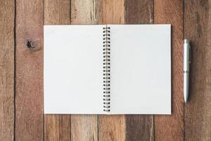 Top view of Blank notebook with pen on wooden table background. photo