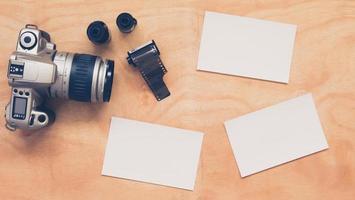 Top view of camera with film and blank postcards on wooden table background. photo