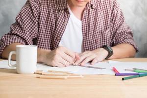 Close up of A man drawing on papers on the wooden table. photo