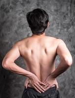 a man with back pain on grey background photo