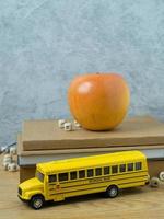 The school bus toy and apple on wood table for back to school or education concept photo