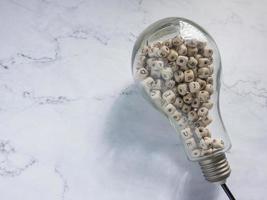 light bulb and alphabet wood cube on white marble for idea or think concept photo