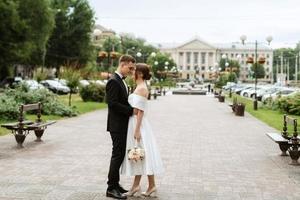 young couple bride and groom in a white short dress photo