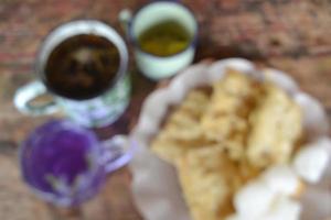 Blurred Photo Of A Plate Of Fried Tempeh And Geblek On The Wooden Table