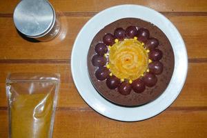 vista de ángulo alto de pudín de chocolate con topping de flores de naranjas y uvas foto