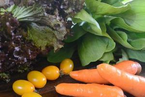 Close up, Purple Lettuce, Caisim, Carrots, and Tomato Placed On A Wooden Table photo