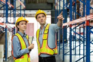 Engineer wearing safety vest controlling machine working talking with assistant engineer worker checking safety first for labour workers. Safety officer check box in warehouse. photo