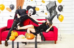 feliz concepto de fiesta de halloween. joven y mujer vestidos como vampiros, brujas o fantasmas celebran el festival de halloween foto