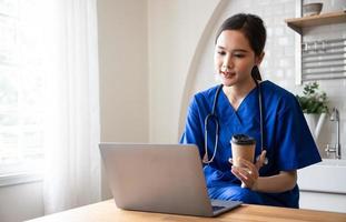 Doctor in blue scrubs and stethoscope relaxing with her laptop on coffee break. Service mind and leisure after hard working