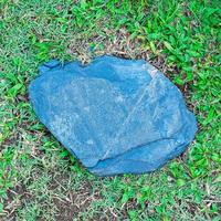 una vieja losa de piedra áspera colocada en un césped verde como placa para una sesión de fotos al aire libre.