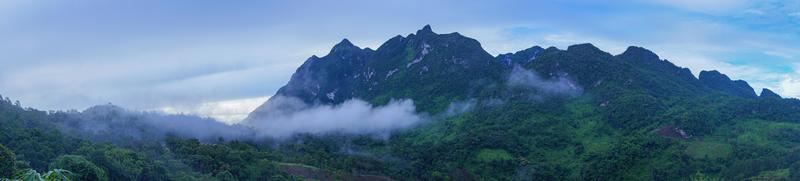 panorama de la montaña verde. hay niebla en medio de la montaña y en la cima de la montaña foto