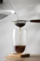 Filtering tea in cup on wooden table photo