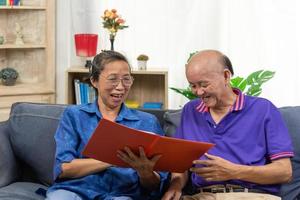 Senior asian couple talking happy planing retirement insurance health care contract on sofa. photo