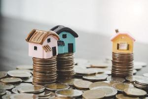 modelo de casa y pilas de monedas de dinero en el fondo de la mesa borrosa. planes de ahorro para vivienda, préstamo, inversión, hipoteca, finanzas y banca sobre el concepto de casa. foto