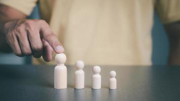 Businessman pointing to the largest wooden doll Business growth and job success ideas which has set strategies and developed efficiency in many areas for leadership in that business photo