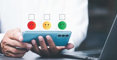 Male consumers use mobile phones to assess their satisfaction and provide online ratings and opinions, customer experience survey concepts for service and product use, and customer engagement. photo