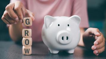 Young girl holding a wooden cube with a piggy bank next to it, concept of growth, finance and investment. that focuses on saving money and managing and planning income from the profit of the business photo