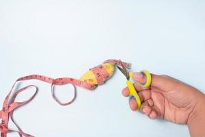 small banana and measuring tape to be cut using scissors, small male genitalia concept photo