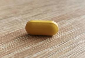 Single pill, dietary supplement on wooden table photo