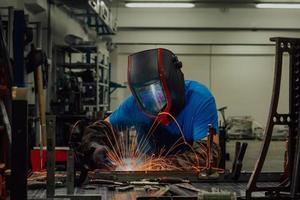 Professional Heavy Industry Welder Working Inside factory, Wears Helmet and Starts Welding. Selective Focus photo