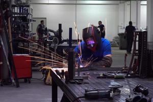 soldador profesional de la industria pesada que trabaja dentro de la fábrica, usa casco y comienza a soldar. enfoque selectivo foto