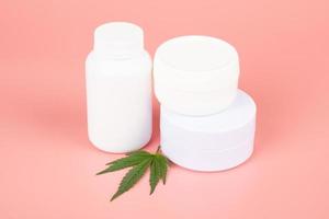 medical cosmetic set based on marijuana, white bottles with lotion and cream and green marijuana leaf photo