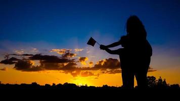 Ukrainian victory concept, silhouette of a mother with a child holding a flag against a blue-blue sky photo