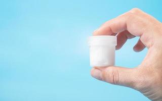 sperm donation concept, a test tube with a white liquid in hand copy space  on a blue background photo