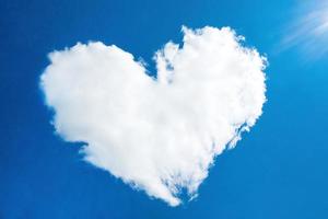 heart in the form of a cloud against the blue sky with the rays of the sun, out of focus photo