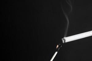 Encender un cigarrillo con una cerilla encendida en blanco y negro. foto