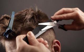 peluquero cortó el cabello del hombre, corte de pelo moderno con tijeras foto