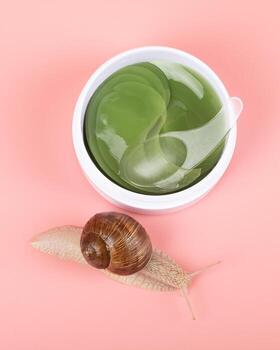 snail and container with cosmetic patches for the eyes with the addition of mucin photo