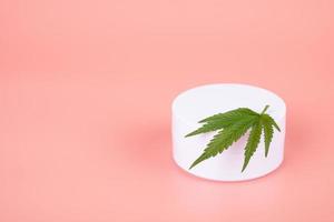 cbd moisturizer and cannabis green leaf on pink background,medical cream with the addition of marijuana extract photo