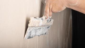 hand application of wall putty with a spatula closeup, plaster repair work photo