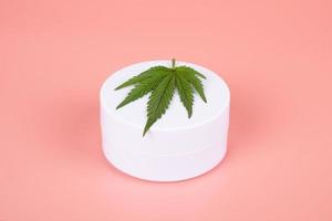 cannabis cosmetics , natural marijuana cream and green leaf on beauty pink background photo