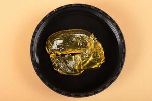 golden cannabis wax in a glass container, high thc dab in glass bottle photo