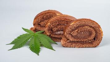 rollo de cannabis de chocolate con extracto de thc y cbd. galletas con marihuana sobre fondo gris foto