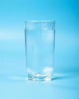 clean water in a glass beaker closeup on a blue background photo