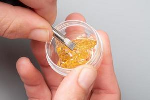 golden cannabis wax in female hands in a box, strong thc extract photo