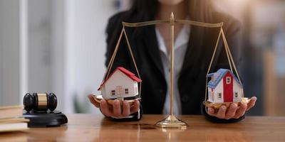 Female lawyer protecting a house model on a scales of justice. Property and legal concept. Houses Litigation. cropped image photo