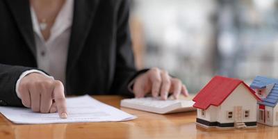 Businesswoman or real estate agent sitting at table with wooden house model and gavel, real estate banner background. photo