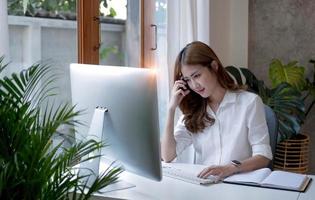 Charming asian businesswoman sitting working on laptop in office. photo