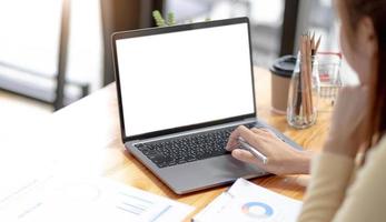 Mockup image of a woman using and typing on laptop computer with blank white desktop screen on wooden table photo