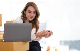 Retrato de mujer joven asiática SM trabajando con una caja en casa el lugar de trabajo.Propietario de una pequeña empresa de inicio, pequeña empresa emprendedora o empresa independiente en línea y concepto de entrega. foto