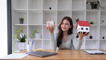 Real estate agent sitting and holding two house model in the office. photo