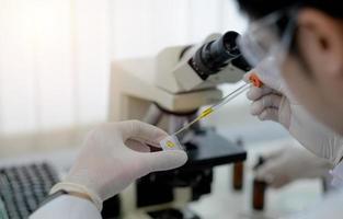 A scientist holding a petri dish in the lab with a monitor and microscope in background. photo