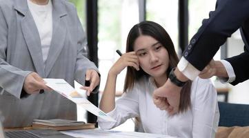 Pretty young Asian female business employee working and planning the marketing campaign with her professional team in the office. photo