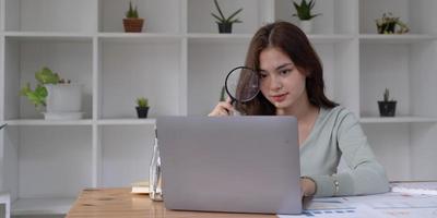 Business analyst using magnifying to review financial graphs, charts. Concept of Analyze return on investment and business analytics growth. photo