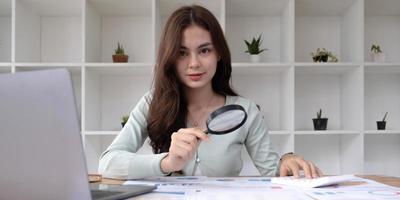 Tax inspector and financial auditor looking through magnifying glass, inspecting company financial papers, documents and reports photo